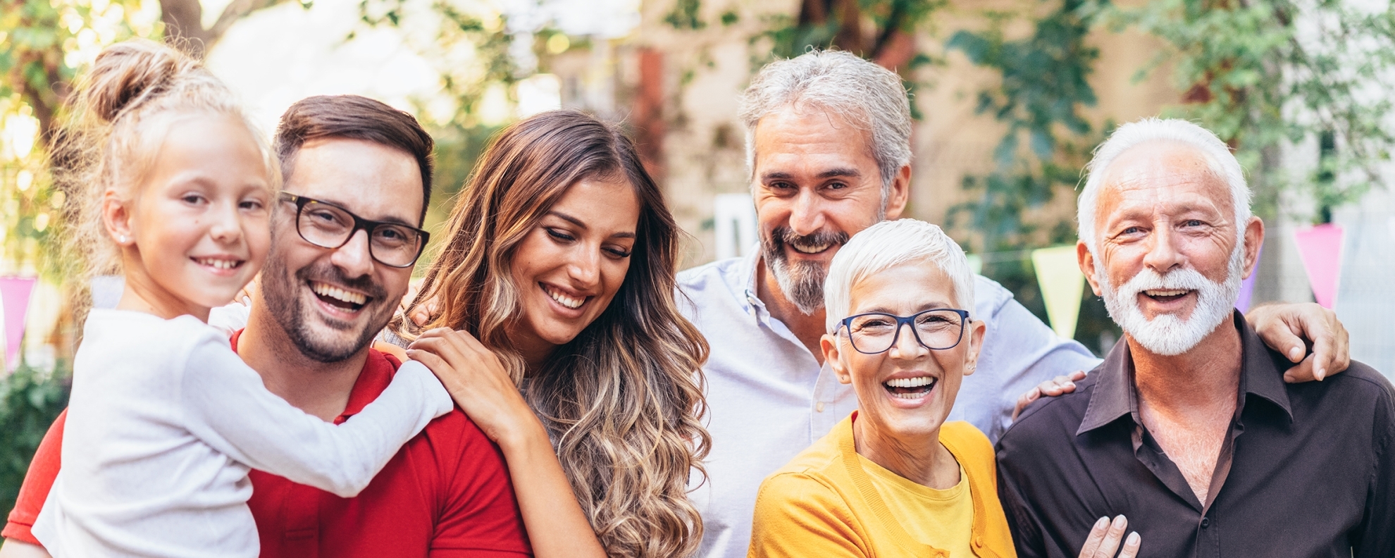 Three generation family - parents, grandparents and children looking at camera and smiling